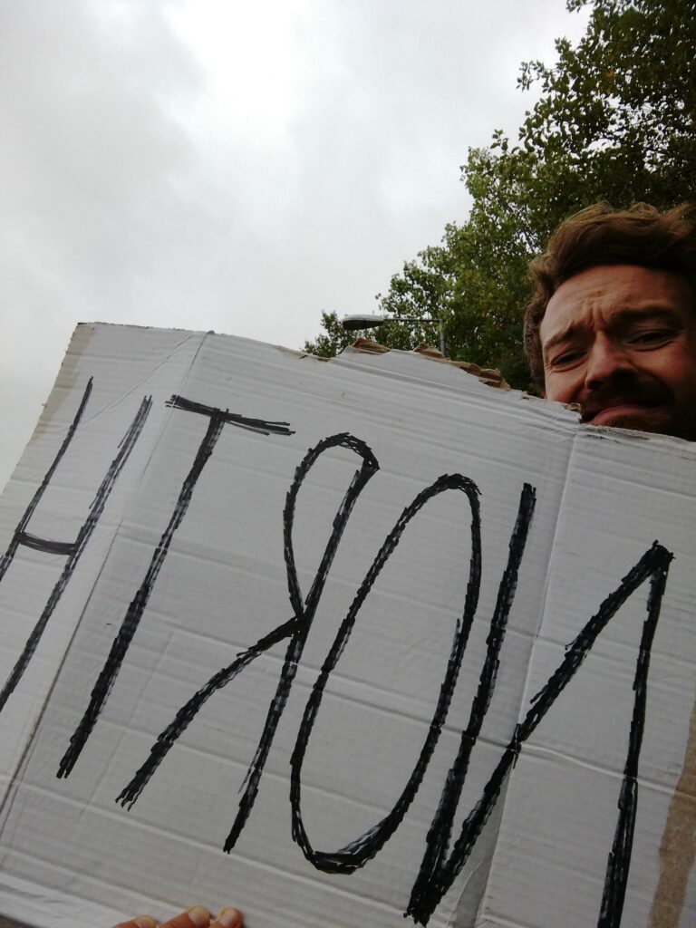 Me, with a sign reading 'north,' from when I was hitchhiking in England